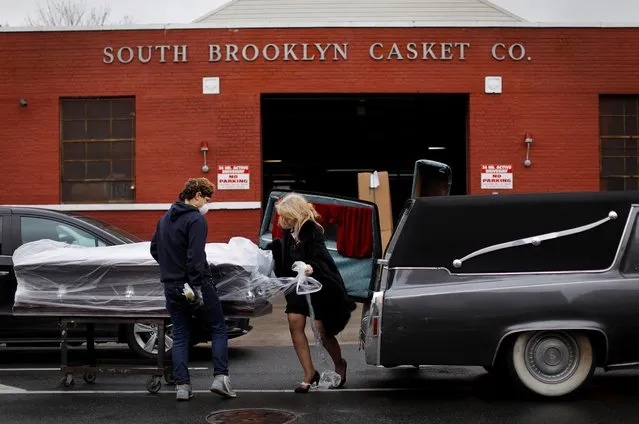 Doris V. Amen, the owner of the Jurek-Park Slope Funeral Home in Brooklyn and a worker from the South Brooklyn Casket Co. load a casket into her 1978 Superior Classic Cadillac hearse for funerals in New York City, New York, April 24, 2020. (Photo by Mike Segar/Reuters)