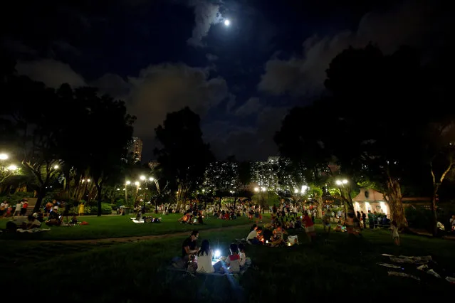 Residents light candles and play with glow sticks under full moon as they celebrate Mid-Autumn or Lantern Festival at a park in Hong Kong, China October 4, 2017. (Photo by Bobby Yip/Reuters)