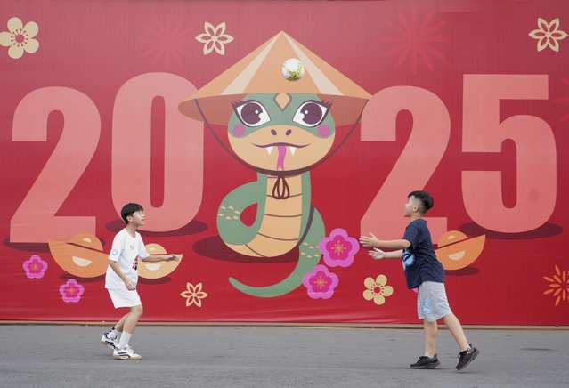 Two boys play football in front of a billboard welcoming the New Year 2025 in Ho Chi Minh city, Vietnam on Tuesday, December 31, 2024. (Photo by Hau Dinh/AP Photo)