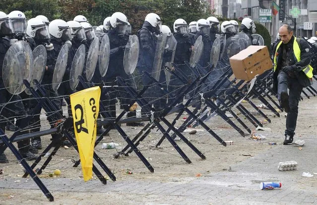 Belgian riot police officers stand guard while a protester throws material as farmers and dairy farmers from all over Europe take part in a demonstration outside an European Union farm ministers emergency meeting at the EU Council headquarters in Brussels, Belgium, September 7, 2015. (Photo by Yves Herman/Reuters)