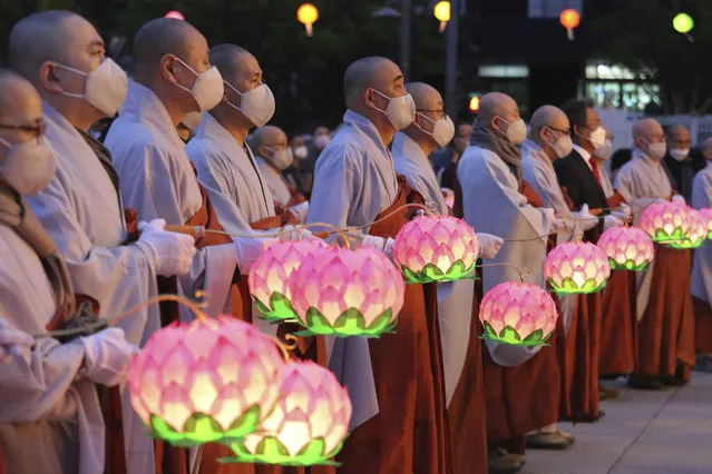 Buddhist monks wearing faces masks to help protect against the spread of the new coronavirus hold lanterns to celebrate the Buddha's birthday at the Gwanghwamun Plaza in Seoul, South Korea, Thursday, April 30, 2020. (Photo by Ahn Young-joon/AP Photo)