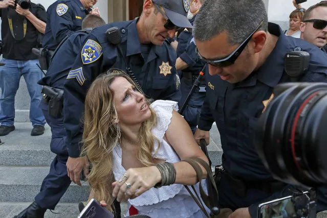 Tara Thornton is detained by California Highway Patrol officers during a demonstration against Gov. Gavin Newsom's stay-at-home orders aimed at slowing the spread of the new coronavirus, at the Capitol in Sacramento, Calif., Friday, May 1, 2020. Several people were taken into custody during the protest calling for Newsom to end the restrictions and allow people return to work. (Photo by Rich Pedroncelli/AP Photo)