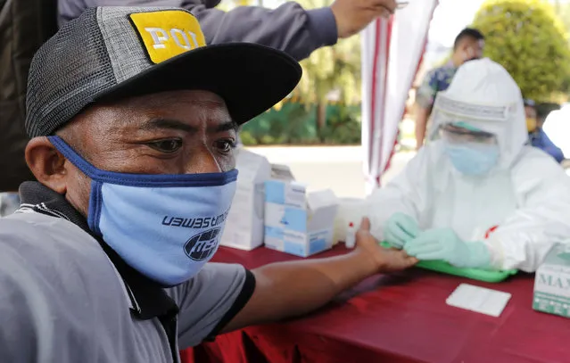 A health worker collects a man's blood sample for the coronavirus antibody test in Bali, Indonesia on Monday, May 11, 2020. (Photo by Firdia Lisnawati/AP Photo)