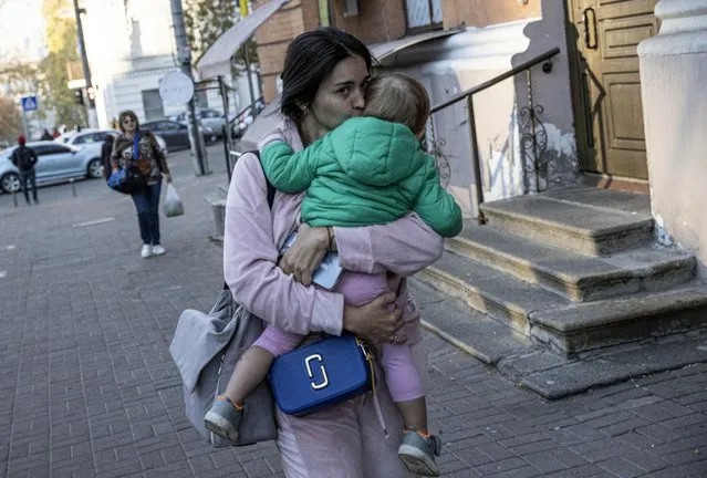 A Ukrainian woman is seen with her child on the sidewalk after the Russian attacks in Kyiv, Ukraine on October 17, 2022. It was reported that explosions occurred in Kyiv due to the attacks carried out by the Russian forces in the early hours of the morning. (Photo by Metin Aktas/Anadolu Agency via Getty Images)