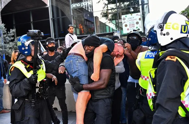 A protester carries an injured counter-protester to safety, near the Waterloo station during a Black Lives Matter protest following the death of George Floyd in Minneapolis police custody, in London, Britain, June 13, 2020. (Photo by Dylan Martinez/Reuters)
