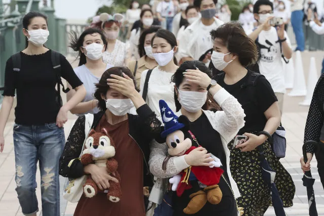People wearing face masks to protect against the spread of the new coronavirus walk toward the entrance to Tokyo Disneyland in Urayasu, near Tokyo, Wednesday, July 1, 2020. (Photo by Koji Sasahara/AP Photo)