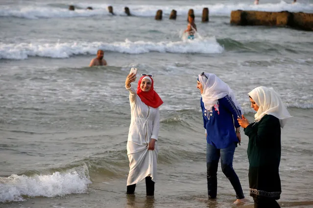 A Muslim woman wearing a Hijab uses her mobile phone to take a photograph as she stands in the Mediterranean Sea at a beach in Tel Aviv, Israel August 30, 2016. (Photo by Baz Ratner/Reuters)