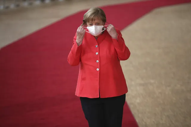 German Chancellor Angela Merkel prepares to remove her protective mask to make a statement as she arrives for an EU summit at the European Council building in Brussels, Friday, July 17, 2020. Leaders from 27 European Union nations meet face-to-face on Friday for the first time since February, despite the dangers of the coronavirus pandemic, to assess an overall budget and recovery package spread over seven years estimated at some 1.75 trillion to 1.85 trillion euros. (Photo by Francisco Seco/AP Photo/Pool)