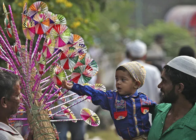 A Muslim boy buys a paper fly-wheel during the celebrations to mark Eid al-Adha in Chandigarh October 6, 2014. (Photo by Ajay Verma/Reuters)
