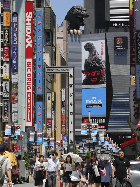 In this July 30, 2016 photo, the poster of “Shin Godzilla”, or “New Godzilla”, is displayed under the monster's head at a movie theater in Tokyo.  Godzilla is back in its homeland of Japan after a 12-year absence, still breathing fire and mercilessly stomping everything in its way. The latest in the giant reptile Godzilla movies opened in Japan on July 29 and is promised for the U.S. and other countries later this year. (Photo by Koji Sasahara/AP Photo)