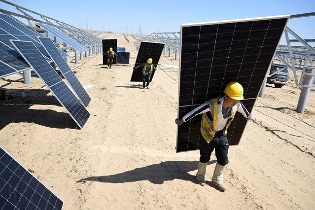 Workers in Lingwu, China, carry solar panels to be installed as part of a 1-million-kilowatt photovoltaic project in the desert on Monday, April 14, 2025. (Photo by AFP Photo/China Stringer Network)