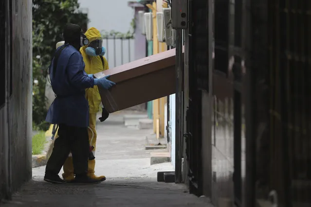 Funeral workers remove the body of a person who is suspected to have died from symptoms related to the new coronavirus, in Quito, Ecuador, Friday, August 14, 2020. The numbers of those infected with COVID-19 have been rising in the capital. (Photo by Dolores Ochoa/AP Photo)