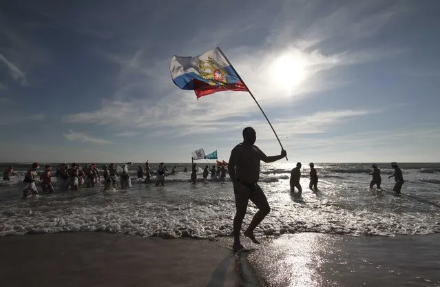 A fan of winter swimming holds the Russian national flag during an event, marking Orthodox Christmas, in the Black Sea port of Yevpatoriya, Crimea January 7, 2018. (Photo by Pavel Rebrov/Reuters)