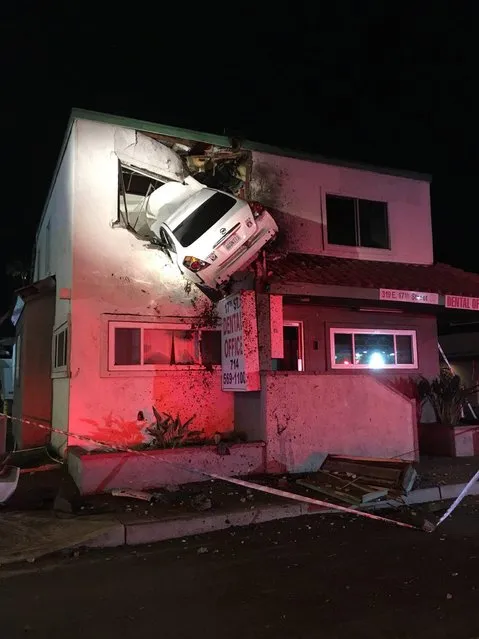 A handout photo made available by the Orange County Fire Authority (OCFA) shows the scene of an accident where a car crashed into the second floor of an office building in Santa Ana, California, USA, 14 January 2018 (issued 15 January 2018). Two passengers were slightly injured after their vehicle hit a center divider and went airborne, crashing into the second floor of a building. (Photo by EPA/EFE/Orange County Fire Authority)