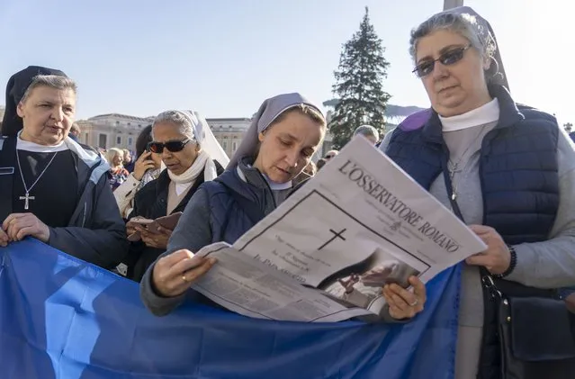Nuns read the Vatican newspaper L'Osservatore Romano bearing the news of the death of Pope Emeritus Benedict XVI as they wait for Pope Francis to appear at his window overlooking St. Peter's Square at The Vatican for the traditional noon blessing, Sunday, January 1, 2023. Pope Benedict, the German theologian who will be remembered as the first pope in 600 years to resign, has died, the Vatican announced Saturday Dec. 31, 2022. He was 95. (Photo by Domenico Stinellis/AP Photo)