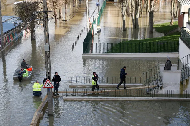 Municipal employees assists residents who walk on elevated boards as the Marne River overflows its banks in Gournay-sur-Marne, near Paris on February 2, 2018. (Photo by Gonzalo Fuentes/Reuters)
