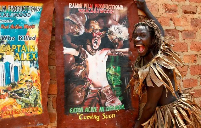 In this photo taken Wednesday, September 7, 2016, actor Francis Kagoro pulls a face for the camera while showing posters of previous movies, at the “Wakaliwood” studios in the Wakaliga slum of Kampala, Uganda. Deep in this Kampala slum at a tin-roofed collection of houses known as Wakaliwood, is the engine of Uganda's tiny film industry and the source of $200-budget movies and a glimmer of fame. (Photo by Stephen Wandera/AP Photo)
