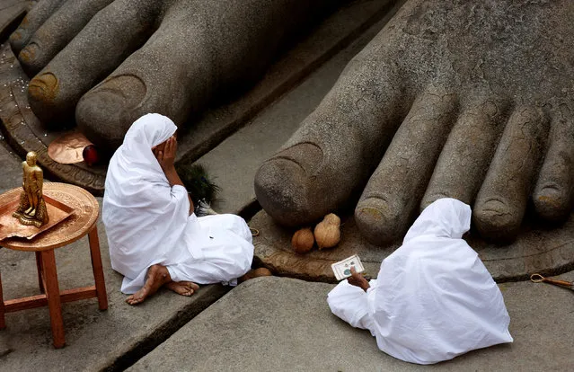 Devotees sit at the feet of the monolithic statue of Jain god Gomateshwara as they celebrate the Mahamastakabhisheka, or head anointing ceremony of the statue, in Shravanabelagola, India February 17, 2018. (Photo by Abhishek N. Chinnappa/Reuters)