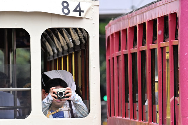 A child takes photos on a tram in Western district of Hong Kong on July 15, 2025. (Photo by Peter Parks/AFP Photo)