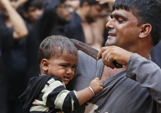 An Indian Shiite Muslim makes a cut on the forehead of a child with a knife during a Muharram procession in Ahmadabad, India, Sunday, October 9, 2016. (Photo by Ajit Solanki/AP Photo)