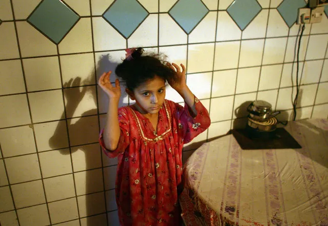 An Iraqi girl holds her hands up while U.S. and Iraqi soldiers search her family house in Baquba, June 30, 2007. (Photo by Goran Tomasevic/Reuters)