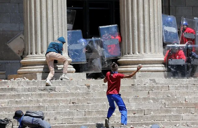 A demonstrator hurls rocks at shield-wielding private security guards during student protests demanding free education at the Johannesburg's University of the Witwatersrand, South Africa, October 10,2016. (Photo by Siphiwe Sibeko/Reuters)