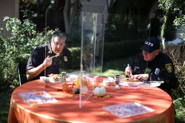 Fire Chief Andrew Wordin and EIT Andrew Muniz eat lunch behind protective glass at a MTO School of Sufism in LA lunch for essential workers, as the global outbreak of the coronavirus disease (COVID-19) continues, in Los Angeles, California, U.S., November 17, 2020. (Photo by Lucy Nicholson/Reuters)