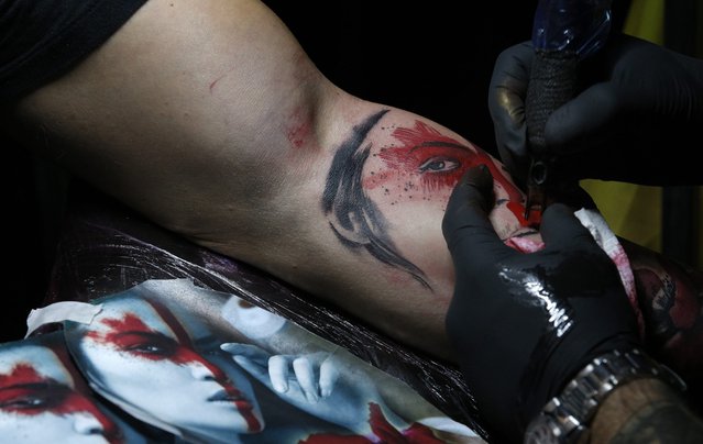 An unidentified tattoo artist works on a customer during a tattoo convention in Bucharest, Romania, 15 October 2016. (Photo by Robert Ghement/EPA)