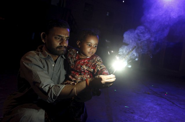 A man holds a sparkler with his child during the Hindu festival of Diwali at the Shri Panchmukhi Temple in Karachi, Pakistan, November 11, 2015. (Photo by Akhtar Soomro/Reuters)