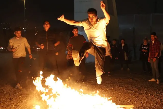 An Iranian jumps over a bonfire during the Wednesday Fire feast, or Chaharshanbeh Soori, held annually on the last Wednesday eve before the Spring holiday of Nowruz, in Tehran on March 14, 2023 ahead of the Nowruz New Year festival. The Iranian new year that begins on March 20 coincides with the first day of spring during which locals revive the Zoroastrian celebration of lighting a fire and dancing around the flame. (Photo by Atta Kenare/AFP Photo)