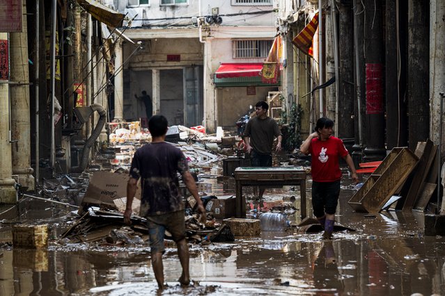This photo taken on June 18, 2024 shows people cleaning the debris in the aftermath of flooding from heavy storms in Meizhou, in southern China's Guangdong province. (Photo by AFP Photo/China Stringer Network)