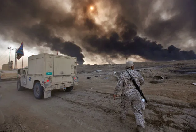 Iraqi army are seen in Qayyara, Iraq, October 22, 2016. The fumes in the background are from oil wells that were set ablaze by Islamic State militants. (Photo by Alaa Al-Marjani/Reuters)