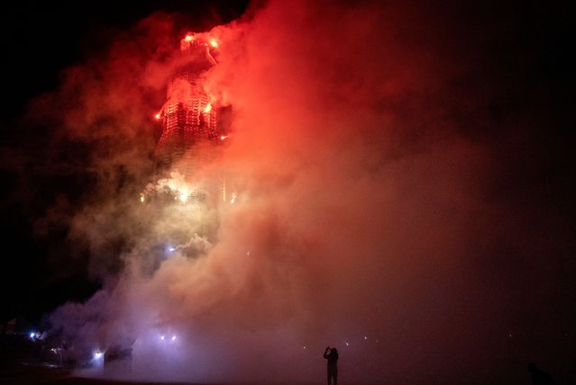 A person stands near the Corcrain Redmanville bonfire as it is set alight on the 'eleventh night' in order to usher in the Twelfth of July celebrations, held by unionists, in Portadown, Northern Ireland on July 10, 2024. (Photo by Clodagh Kilcoyne/Reuters)