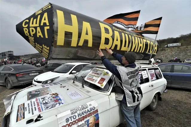 A man decorates his car with a mock-up of a rocket with the inscription “To Washington”, as he prepares to attend a motor rally marking the ninth anniversary of Crimea annexation from Ukraine, in Sevastopol, Crimea, Saturday, March 18, 2023. (Photo by AP Photo/Stringer)