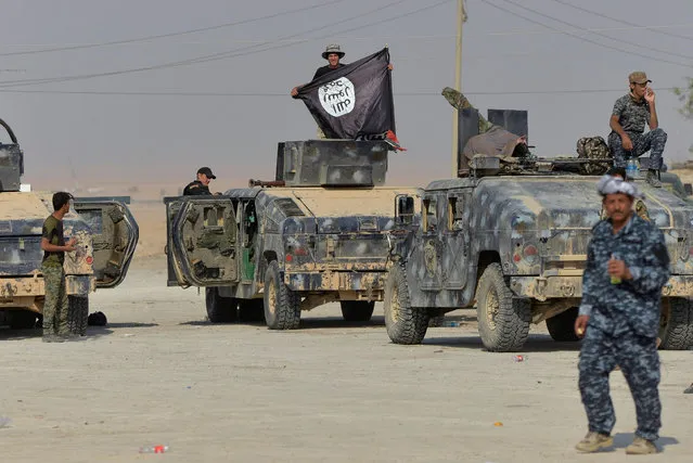 A member of federal police forces holds an Islamic State flag during an operation against Islamic State militants in south of Mosul October 26, 2016. (Photo by Reuters/Stringer)