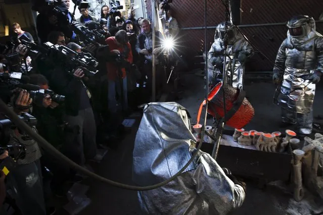 Workers pour a container of molten bronze during a media event on the production of “The Actor” statuette for the 21th annual Screen Actors Guild (SAG) Awards at American Fine Arts Foundry in Burbank, California January 13, 2015. (Photo by Patrick T. Fallon/Reuters)