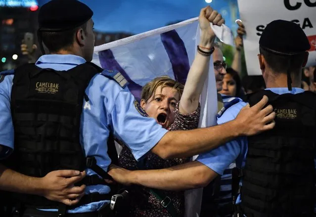 Protesters shout anti-government slogans during a protest in front of the Romanian Government headquarters in Bucharest May 30, 2018. Around 2,000 people gathered in a protest after Romania's Constitutional Court ruled that President Klaus Iohannis must approve the government's dismissal of the country's top anti-corruption prosecutor Laura Kovesi. The government accuses Kovesi of violating the constitution but her supporters say she has been targeted for investigating corruption among Romania's political elite. (Photo by Daniel Mihailescu/AFP Photo)