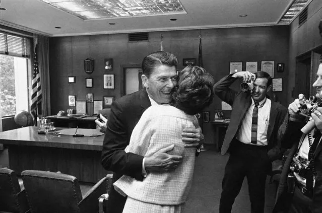 California's Gov. Ronald Reagan gives his wife, Nancy, a surprise hug as she leaves his office in Sacramento on April 27, 1967. At right they are both evidently amused at the startled faces of visitors in the room. Mrs. Reagan was in the Capital helping advise workmen who are redecorating the governor's offices. (Photo by AP Photo)