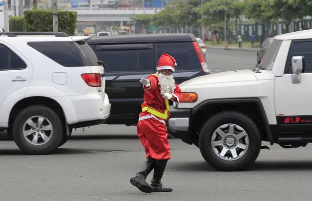 Traffic enforcer Ramiro Hinojas wears a Santa Claus costume while directing traffic flow at a busy intersection in Pasay city, metro Manila, December 12, 2015. Hinojas busts some dance moves while directing traffic to entertain motorists stuck in the congested intersection as holiday-goers crowd malls for their yuletide shopping a few days before Christmas. (Photo by Romeo Ranoco/Reuters)