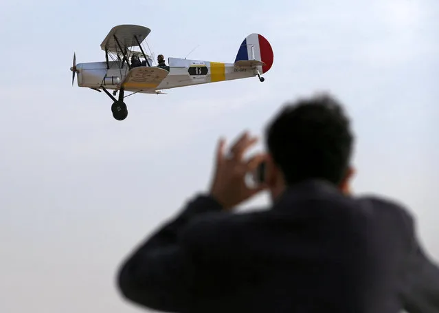 An Egyptian man takes a picture of the biplane flown by Cedric Collette and Alexandra Maingard as it glides by Egypt's iconic pyramids of Giza, on the second leg of their month-long journey through Africa in Cairo, Egypt, November 13, 2016. (Photo by Mohamed Abd El Ghany/Reuters)