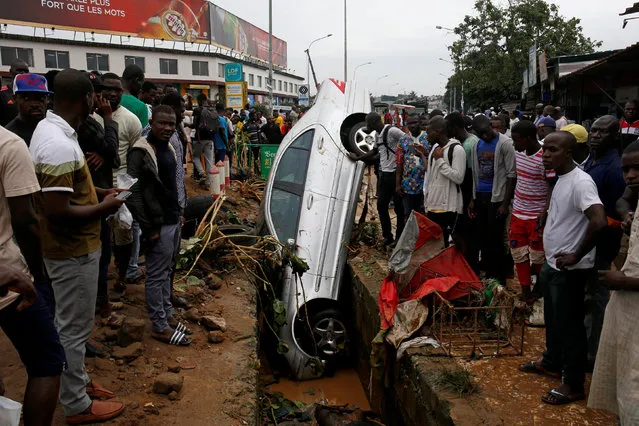 People look at a car in a sewer after a flood in Abidjan, Ivory Coast, June 19, 2018. (Photo by Luc Gnago/Reuters)