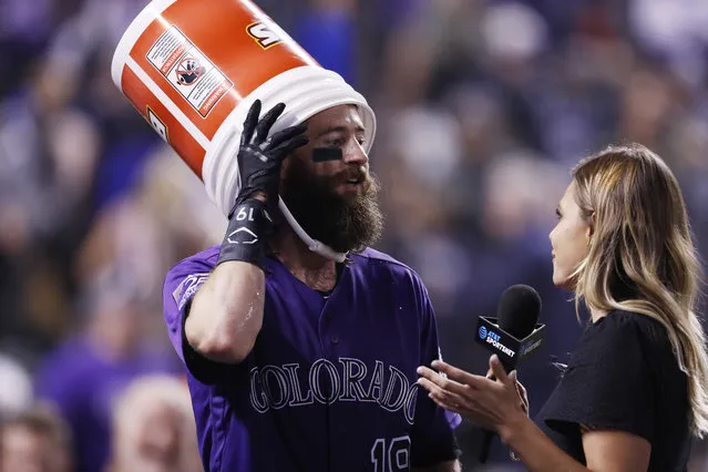 Colorado Rockies' Charlie Blackmon, left, wears a bucket after sunflower seeds were dumped on him by a teammate to mark Blackmon's walk-off solo home run against the Houston Astros in a baseball game Wednesday, July 25, 2018, in Denver. The Rockies won 3-2. On-field television reporter Taylor McGregor is at right. (Photo by David Zalubowski/AP Photo)
