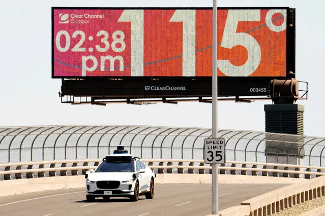 A Waymo self-driving car drives on Seventh Street as the temperature of 115 degrees is displayed on a digital billboard in downtown Phoenix, Arizona, U.S. July 17, 2023. Phoenix hit 114F (45.5C) on July 17, matching a historic record of 18 straight days over 110F with the forecast showing the record likely to extend for at least another week. (Photo by Rob Schumacher/USA Today Network via Reuters)