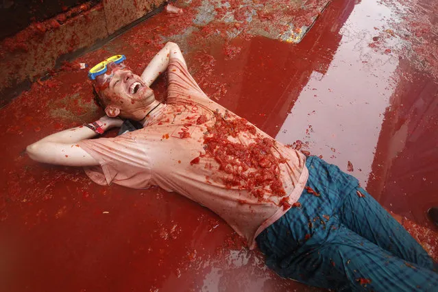 A man lays on a puddle of tomato during the annual “tomatina” tomato fight fiesta in the village of Bunol, 50 kilometers outside Valencia, Spain, Wednesday, August 28, 2013. Thousands of people are splattering each other with tons of tomatoes in the annual “Tomatina” battle in recession-hit Spain, with the debt-burdened town charging participants entry fees this year for the first time. Bunol town says some 20,000 people are taking part in Wednesday's hour-long street bash, inspired by a food fight among kids back in 1945. Participants were this year charged some 10 euros ($13) to foot the cost of the festival. Residents do not pay. (Photo by Alberto Saiz/AP Photo)