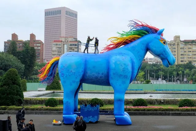 Two journalists stand on the back of a horse-shaped statue on display to promote the art performance titled “Yu Ma” presented by Taiwan’s Paper Windmills Theater, during a photo call outside the Sun Yat-sen Memorial Hall in Taipei on March 24, 2021. (Photo by Sam Yeh/AFP Photo)