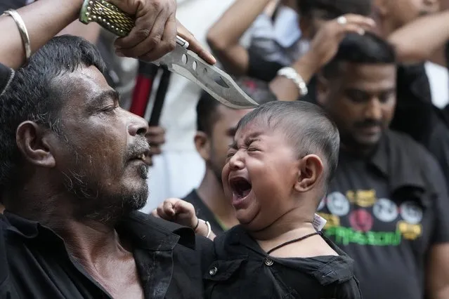A Shiite Muslim touches the forehead of a child with the point of his knife during a Muharram procession in Ahmedabad, India, Wednesday, July 26, 2023. Muharram is a month of mourning for Shiite Muslims in remembrance of the martyrdom of Imam Hussein, the grandson of the Prophet Muhammad. (Photo by Ajit Solanki/AP Photo)