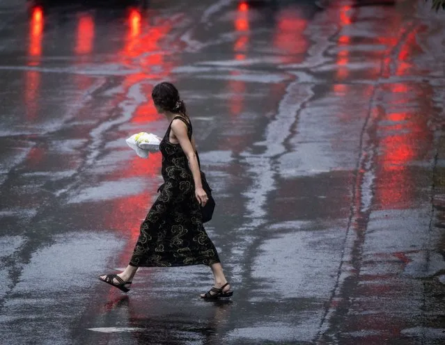 A woman walks bareheaded across rainy Dixon avenue as a large and destructive storm system bears down on the region in Silver Spring, MD on August 7, 2023. (Photo by Bill O'Leary/The Washington Post)