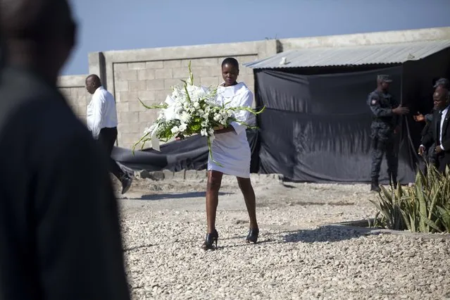 A woman arrives with a floral tribute at Titanyen, the mass burial site for victims of the 2010 earthquake, before the start of a memorial service marking the sixth anniversary of the quake, north of Port-au-Prince, Haiti, Tuesday, January 12, 2016. Haitians gathered at prayer services to remember those who lost their lives. The government has said more than 300,000 people were killed, but the exact toll is unknown. (Photo by Dieu Nalio Chery/AP Photo)