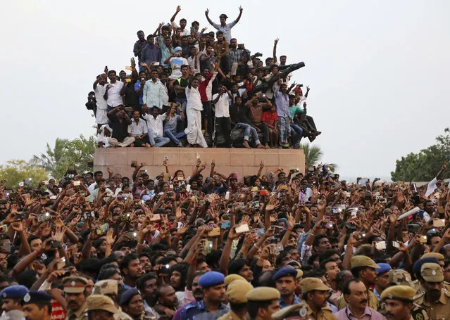 Supporters of India's popular politician and former film actress Jayaram Jayalalithaa react as they watch the casket carrying her body pass in a funeral procession in Chennai, India, Tuesday, December 6, 2016. Jayalalithaa, chief minister of Tamil Nadu state, died overnight following a heart attack a day earlier. (Photo by Aijaz Rahi/AP Photo)