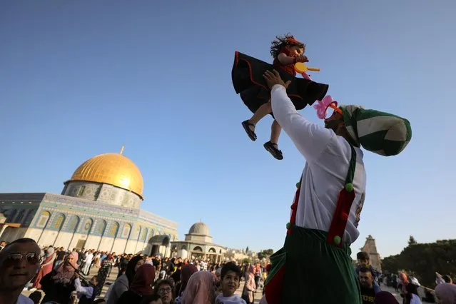 A clown plays with a young girl during Eid al-Fitr prayers, which mark the end of the holy fasting month of Ramadan, at the compound that houses al-Aqsa mosque, known to Muslims as Noble Sanctuary and to Jews as Temple Mount, in Jerusalem's Old City, amid Israel-Gaza fighting May 13, 2021. (Photo by Ammar Awad/Reuters)